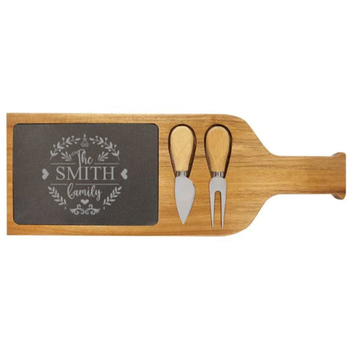 Paddle shape acacia wood cheese board set with knife and fork, embellished with engraved slate family names and monograms.